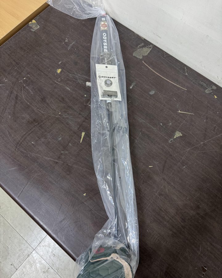 The Odyssey putter with its tag and headcover, sealed in a clear bag